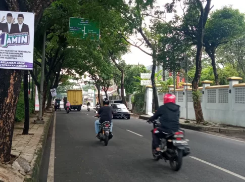 Ketpot: Pengendara saat melewati banner salah satu pasangan calon presiden yang dipaku di batang pohon