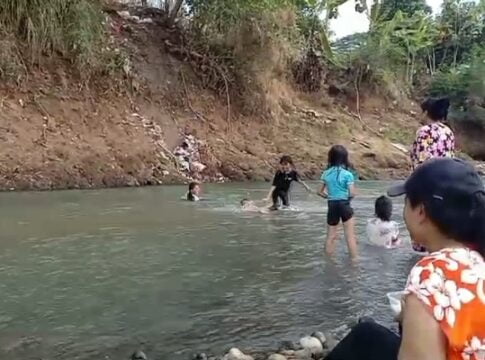 Caption: Bawa Anak-anak, Warga Banjar Tunggu Kemunculan Tank Baja Peninggalan Belanda di Sungai Citanduy.