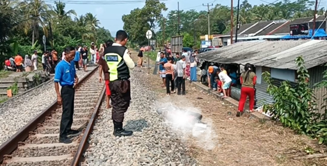 Caption: Warga berkerumun melihat lokasi kejadian tewasnya Ihun akibat tersambar kereta api
