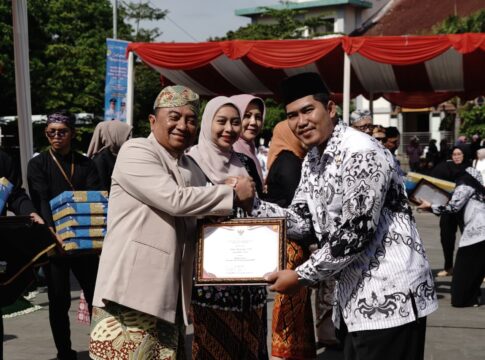 Keterangan Foto: Bupati Garut Abdusy Syakur Amin (kiri) menyerahkan penghargaan kepada salah satu pendidik berprestasi pada Upacara Peringatan Hari Guru Nasional (HGN) dan HUT PGRI ke-80 Tingkat Kabupaten Garut Tahun 2025 di Alun-Alun Garut, Selasa (25/11/2025).