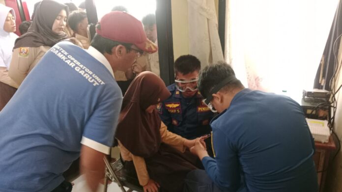 Petugas Damkar berupaya melepas jari siswi yang tersangkut rautan pensil, di SDN 4 Paas, Kecamatan Pamengpeuk, Sabtu (13/12/2025.