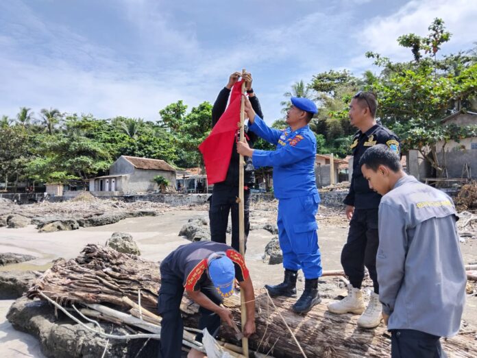 Keterangan Foto: Anggota Satuan Polisi Perairan dan Udara (Sat Polairud) Polres Garut memasang pos pantau, bendera merah, serta spanduk larangan berenang di kawasan wisata pantai selatan Kabupaten Garut, Rabu (24/12/2025). Langkah ini dilakukan dengan guna mencegah terjadinya kecelakaan laut (laka laut) bagi wisatawan.